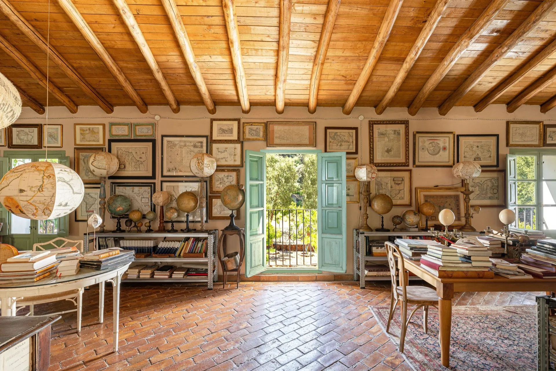 Room with timber beams, framed antique maps and a collection of globes.
